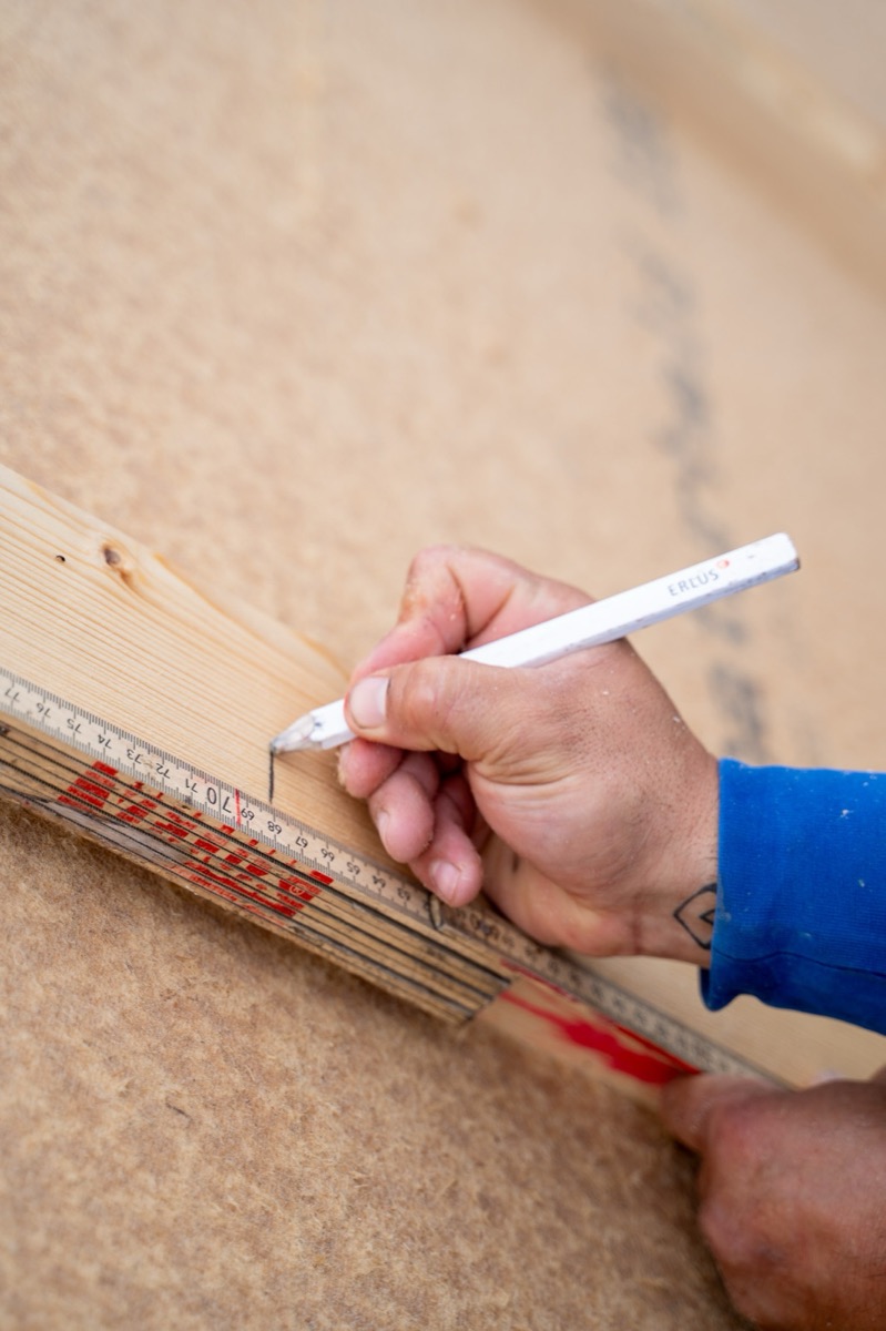 Hand mit Zollstock und Stift beim Anzeichnen